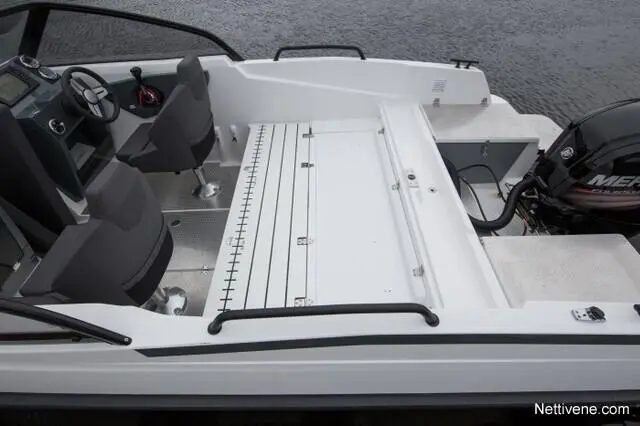 Modern boat interior featuring gray seating, control panel, and storage space, with a black outboard motor visible.